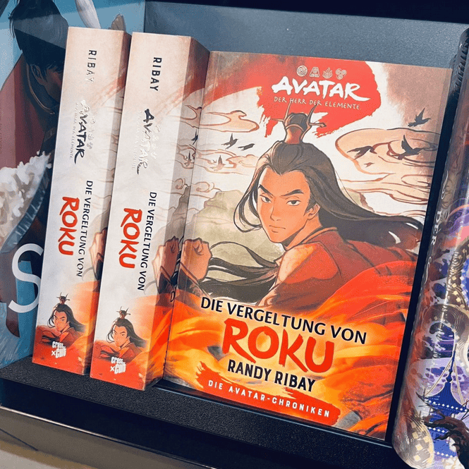 Drei Exemplare des Buchs „Die Vergeltung von Roku“ von Randy Ribay, Teil der „Avatar – Die Herr der Elemente“-Roman-Reihe. Das Cover zeigt eine Figur mit langen Haaren in roter Kleidung vor einem Hintergrund mit fliegenden Kreaturen und Wolken. 